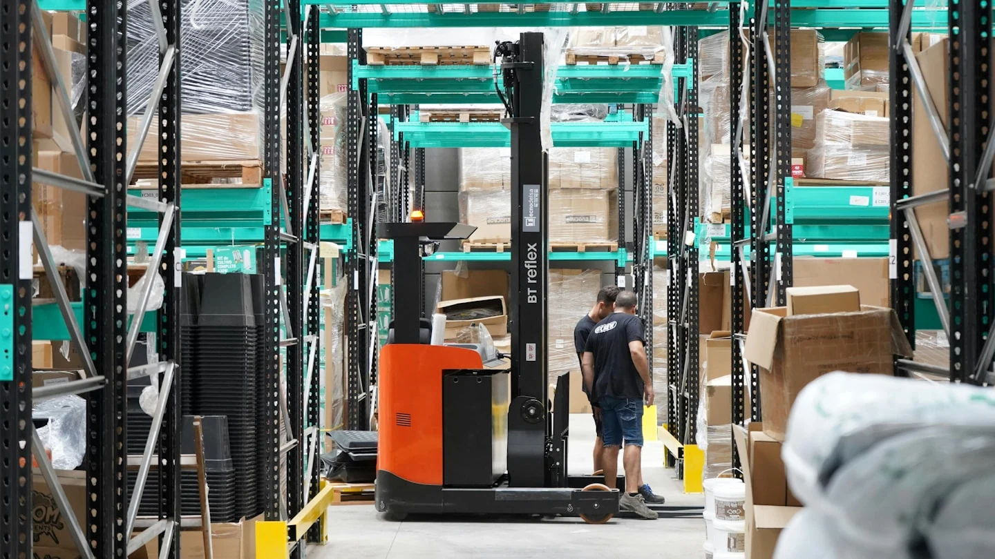 A man standing in a warehouse with a fork lift